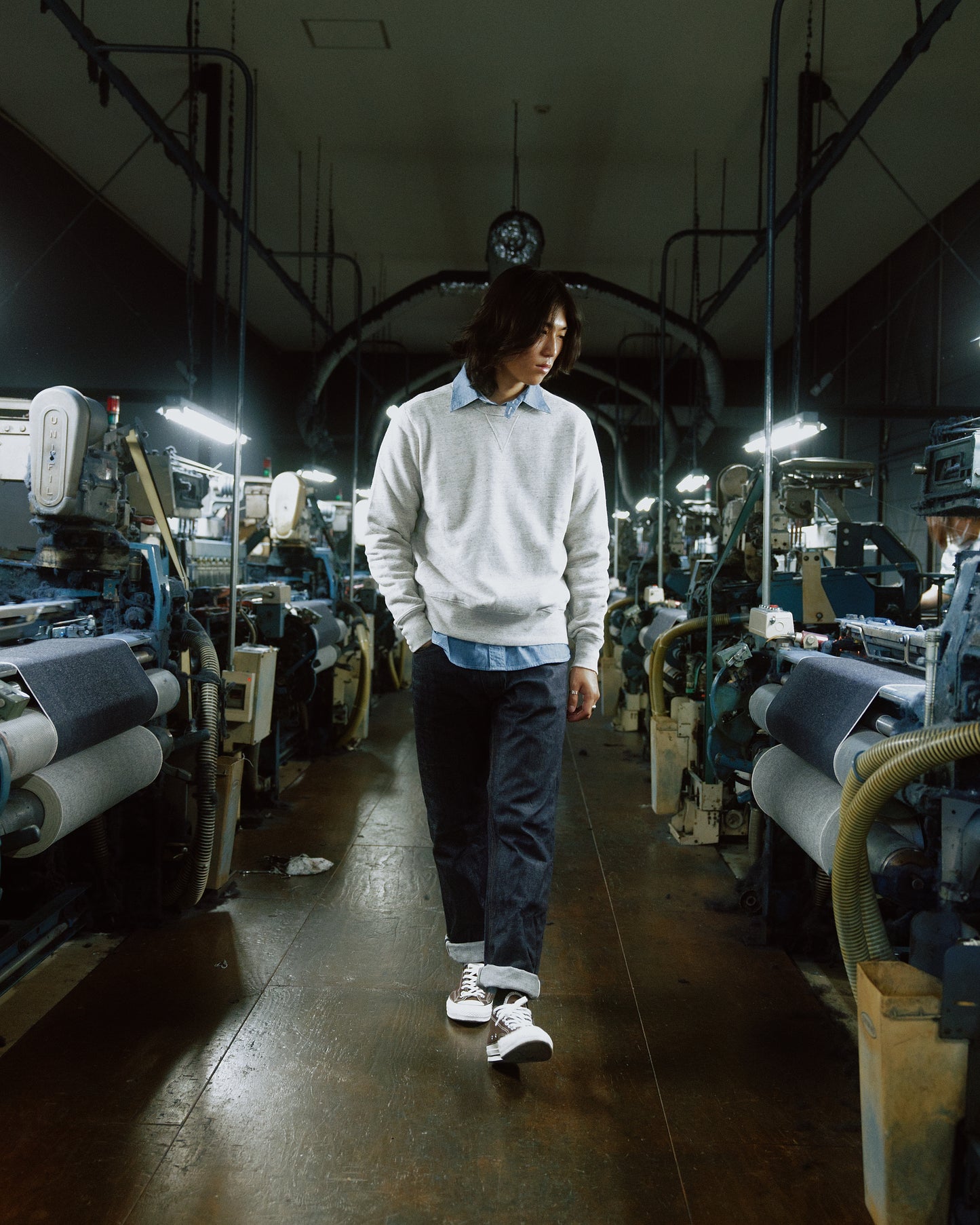 Homme portant un jean selvedge japonais authentique dans une usine traditionnelle, illustrant l'artisanat et la qualité exceptionnelle du denim japonais.