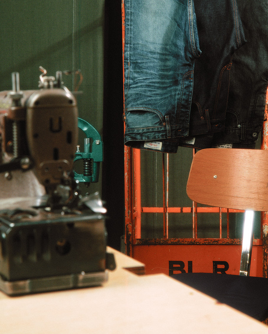 jeans selvedge posés sur un portant ancien de couleur orange, dans un atelier de denim à toulouse 