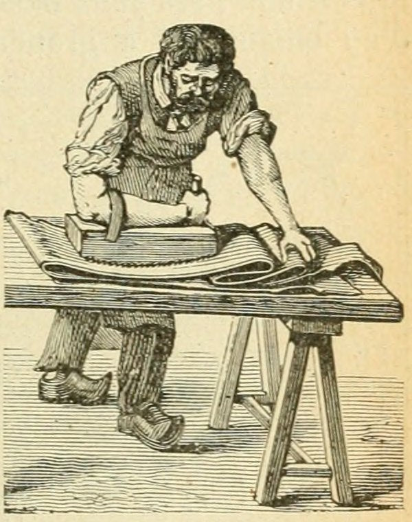 Artisan travaillant le cuir pour créer la texture du daim ou du velours sur une table, utilisant un outil pour rendre la matière aussi douce que du velours.
