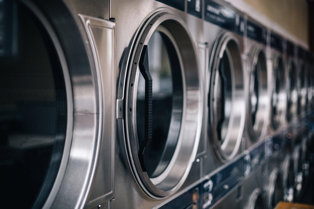 Une rangée de machines à laver industrielles en acier inoxydable, soulignant l’importance de comprendre les symboles de lavage pour un entretien approprié