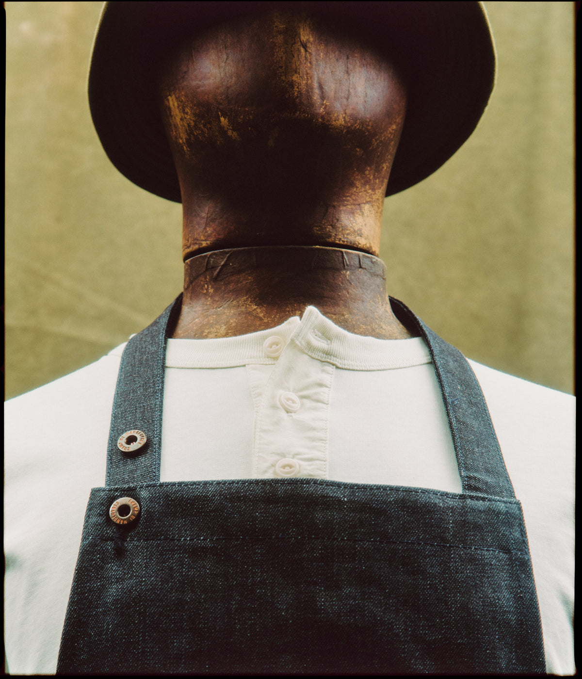 Bavette du Tablier de métier en denim selvedge portée sur un henley blanc, boutons pression en gros plan