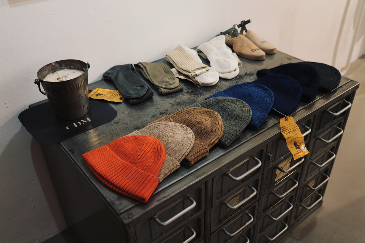 Bonnets et casquettes exposes sur un meuble d'atelier, boutique Champ de Manœuvres a Toulouse