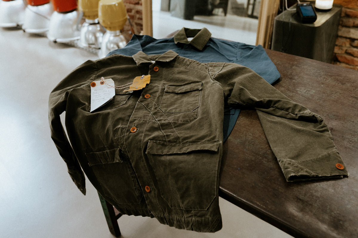 Vestes de travail pliees sur une table de la boutique Champ de Manœuvres a Toulouse