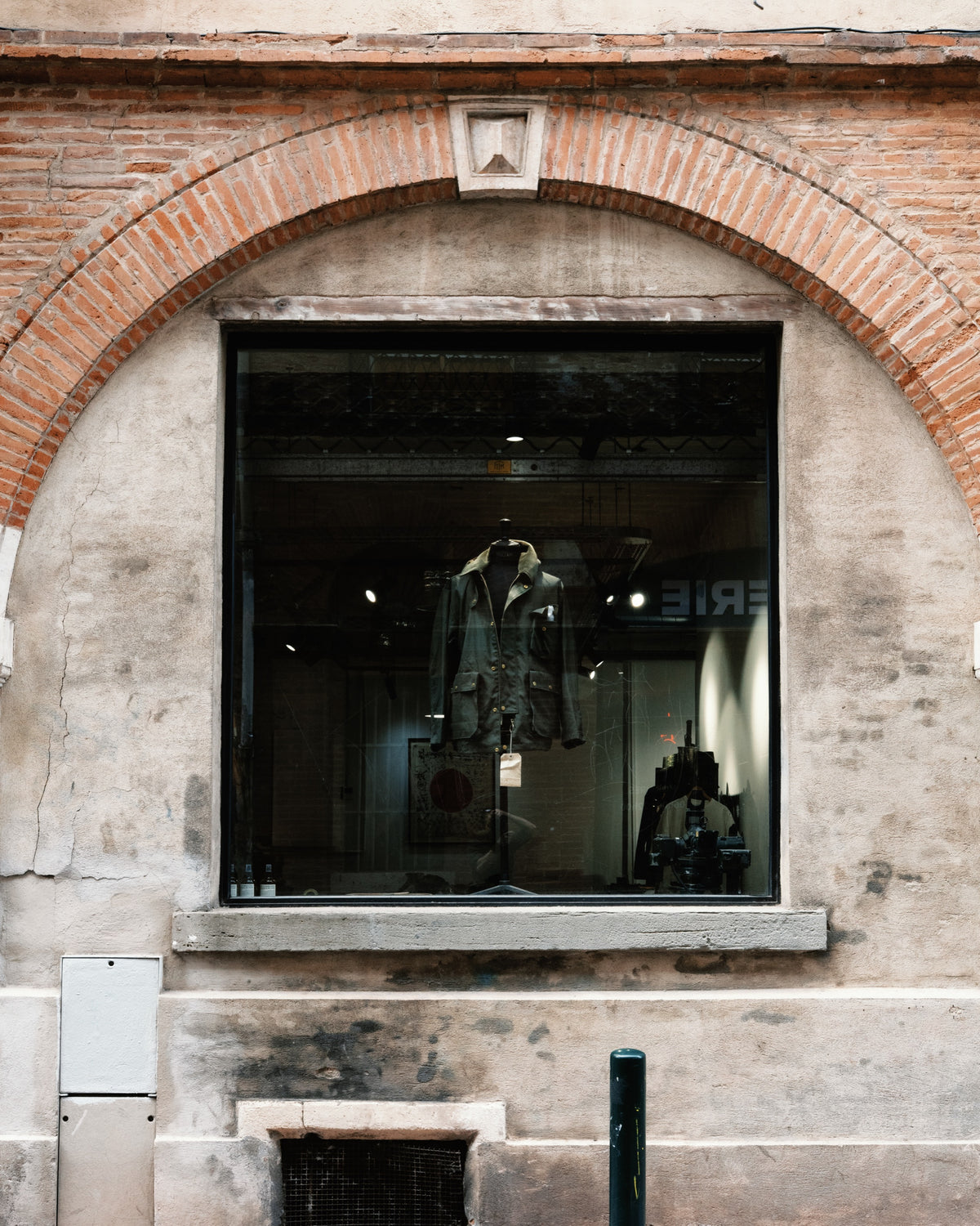 Veste de travail en vitrine sous l'arcade en brique de la boutique Champ de Manœuvres a Toulouse
