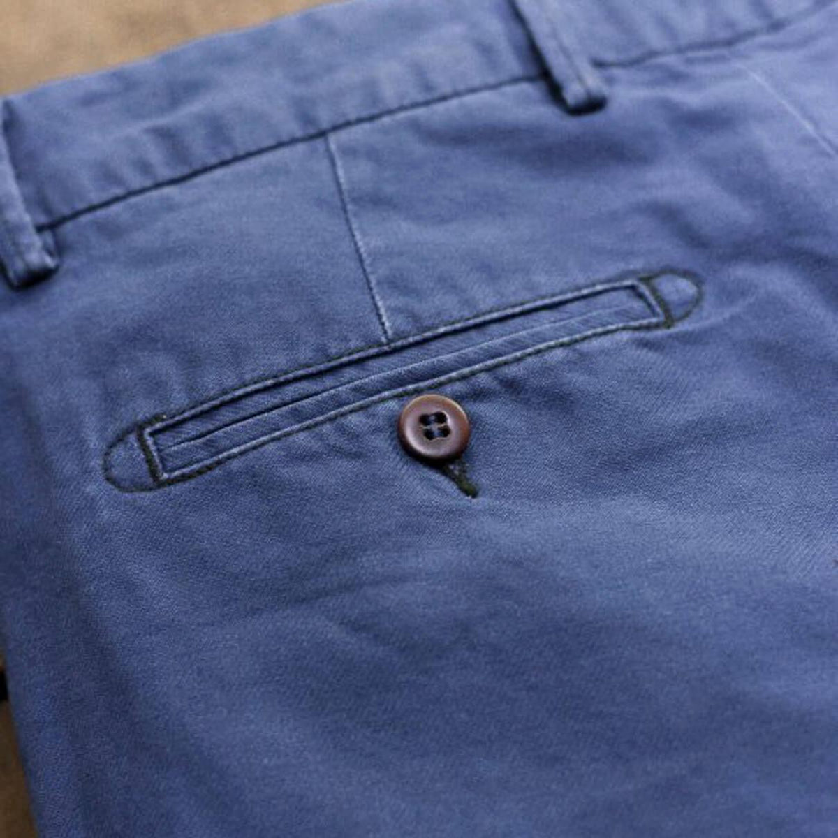 Détail de la poche arrière passepoilée du Chino Slack Hydron, bouton corozo brun et passant de ceinture