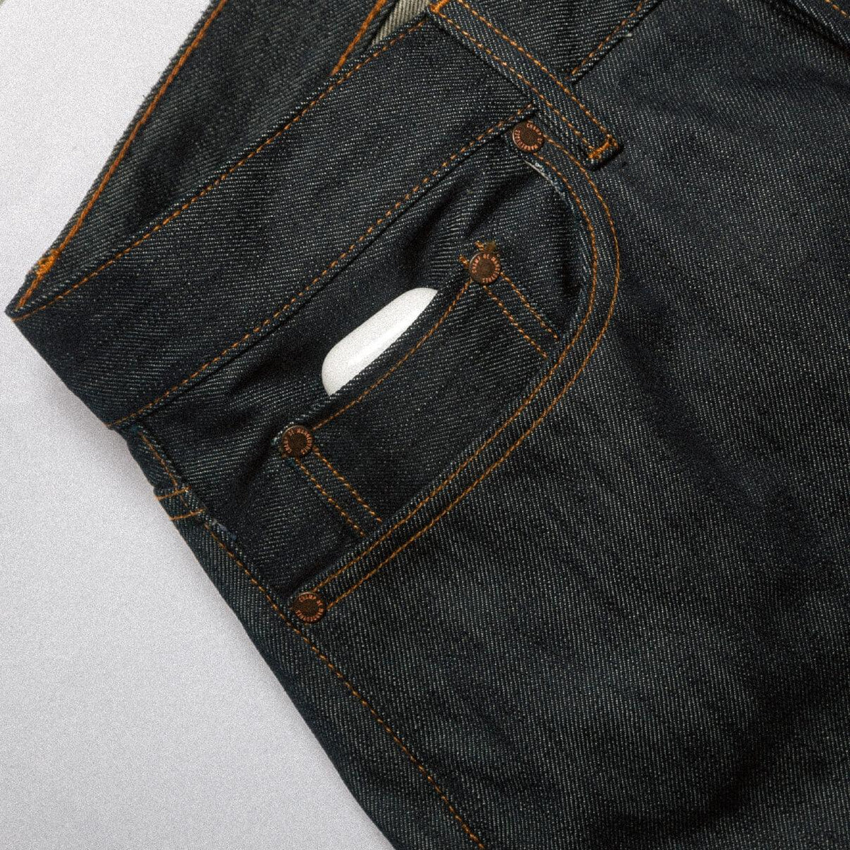 Détail de la poche gousset du Jeans selvedge 13 oz brut, rivets de cuivre et surpiqûres orange