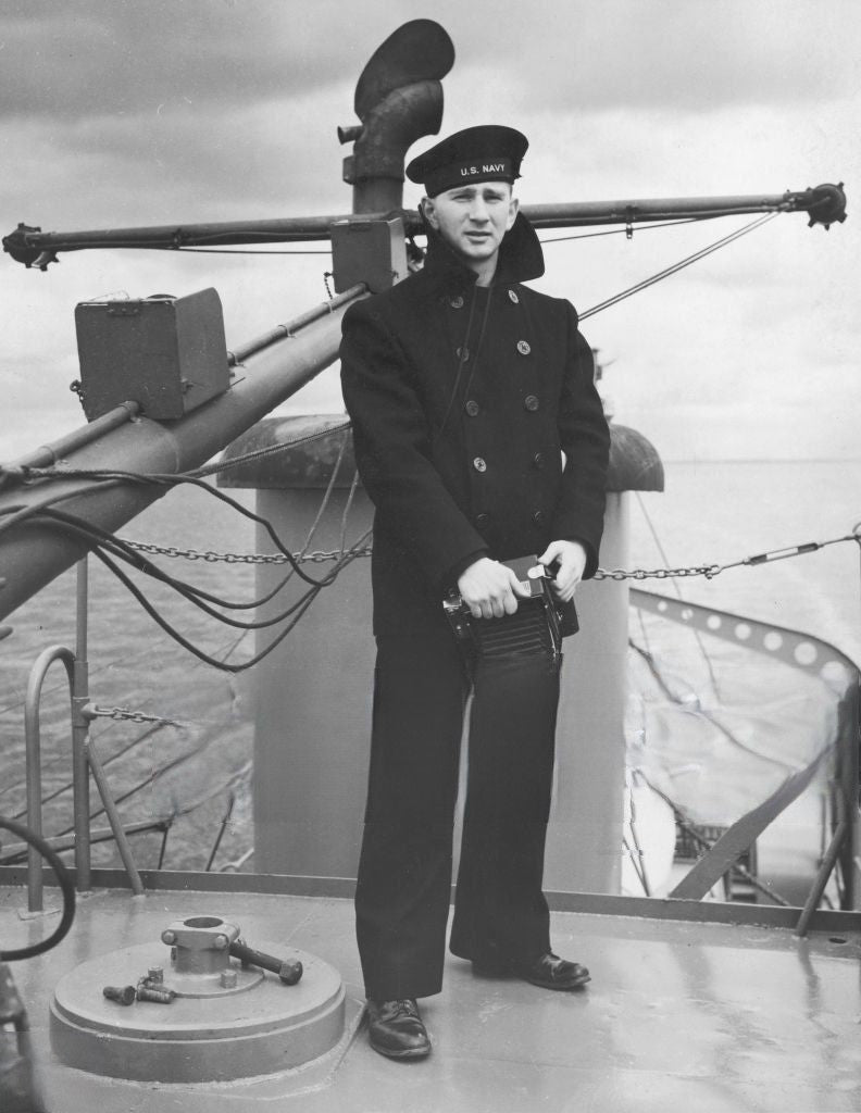 Marin américain portant un caban de type peacoat sur un bateau en mer.