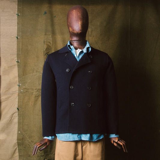 veste croisée en laine tricotée portée par un stockman dans un atelier de style militaire.