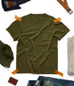 T-shirt kaki homme à poche posé à plat, entouré d'une veste en jean brut, d'une ceinture en cuir et d'un bob