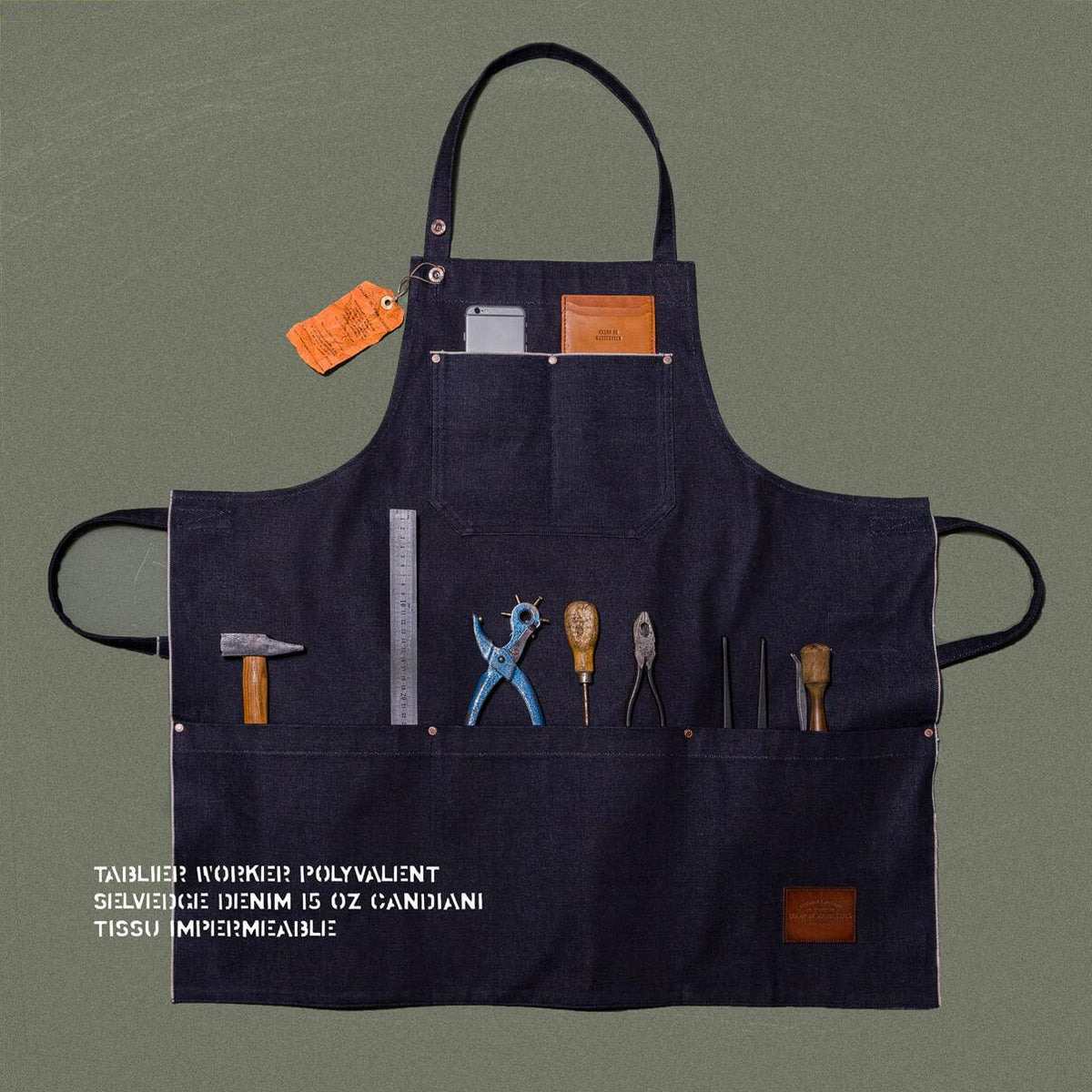 Tablier de métier en denim selvedge 15 oz déployé, poches garnies d'outils, patch de cuir et étiquette orange